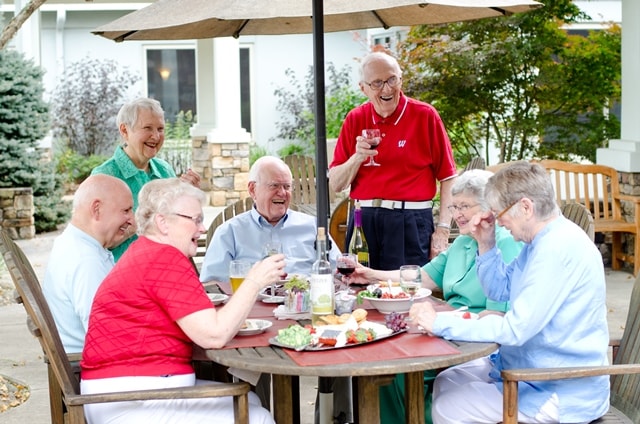 Elderly people sitting at a patio table outside 